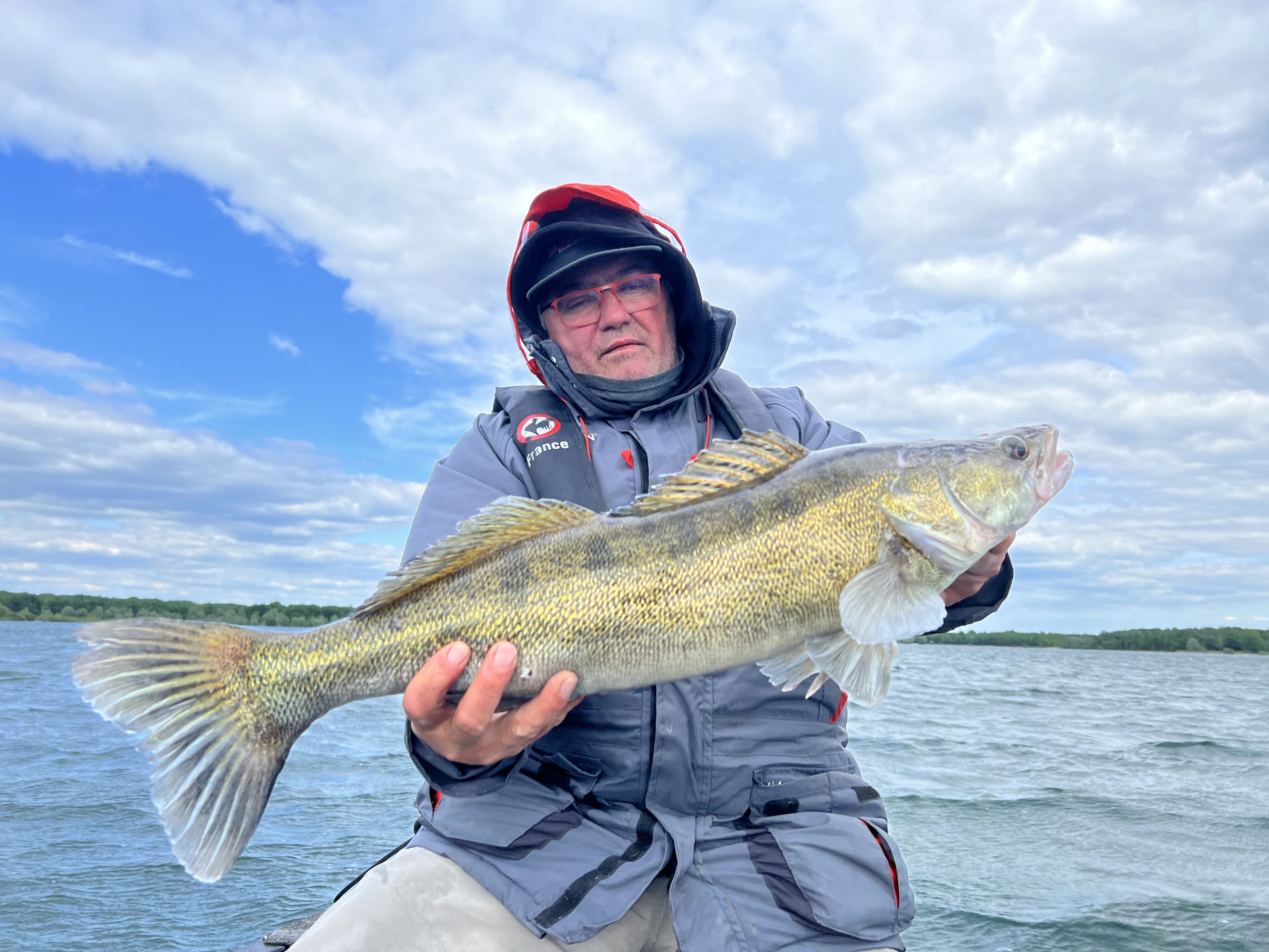 Patrick souriant, tenant un joli sandre capturé lors d’une sortie de pêche guidée sur le Lac du Der Patrick souriant, tenant un joli sandre capturé lors d’une sortie de pêche guidée sur le Lac du Der, avec le soutien de la technologie Megalive de Navicom.
