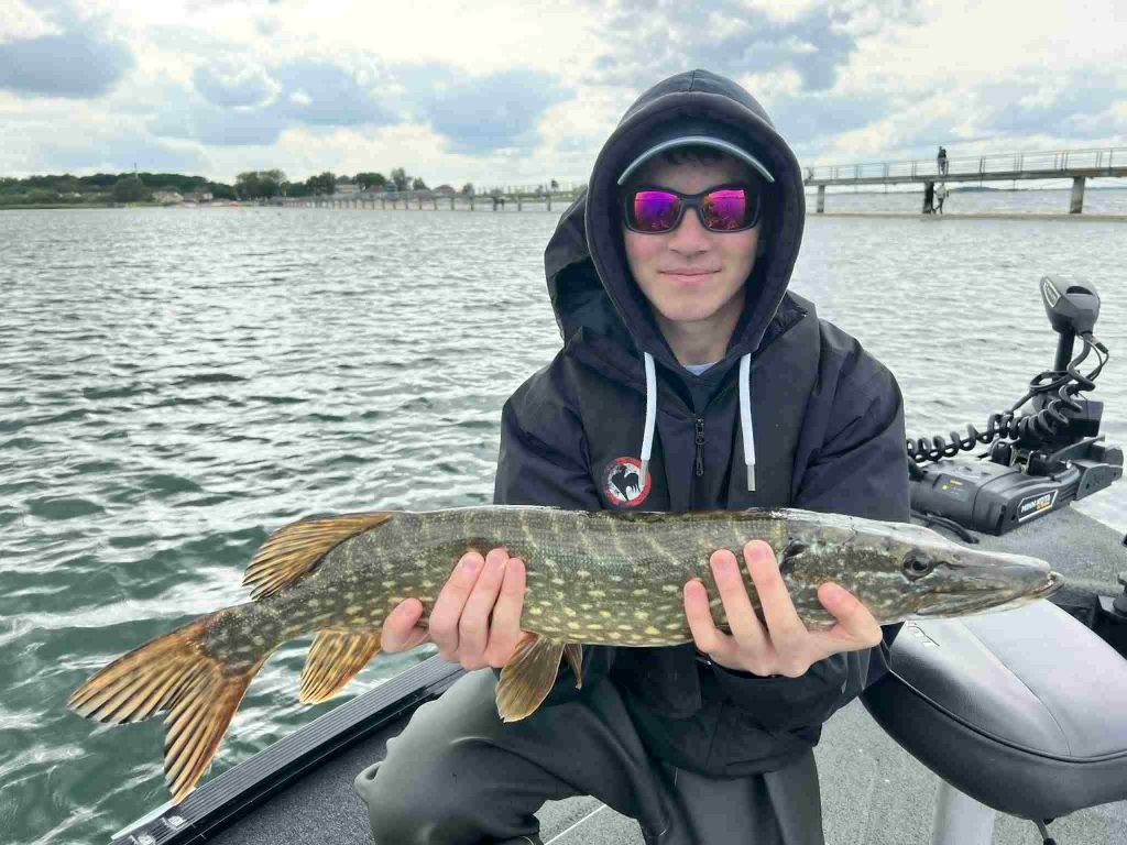 Côme, jeune pêcheur, tient un brochet capturé sur le lac du Der