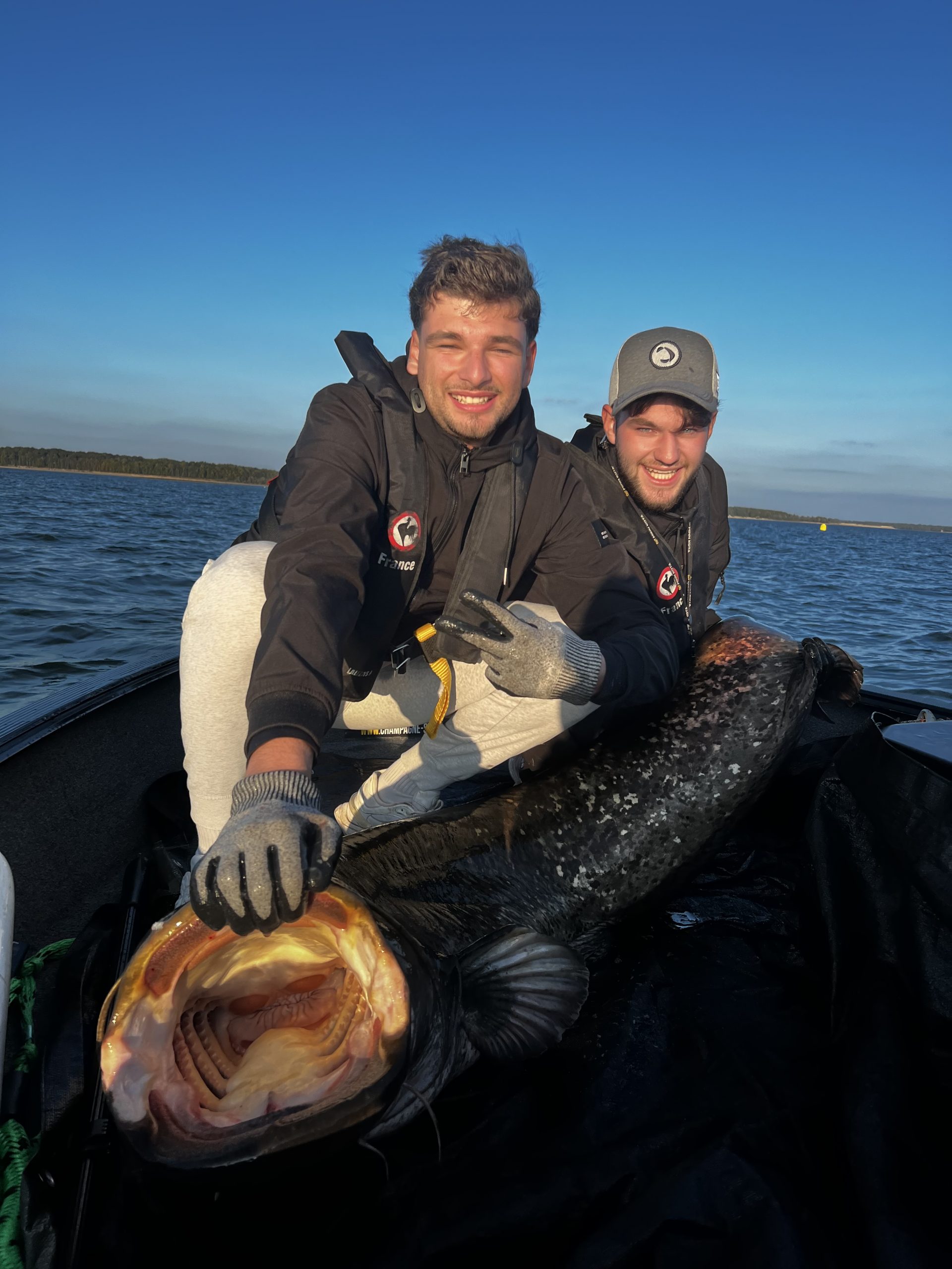 Deux jeunes pêcheurs présentant un grand silure au bord du lac du Der