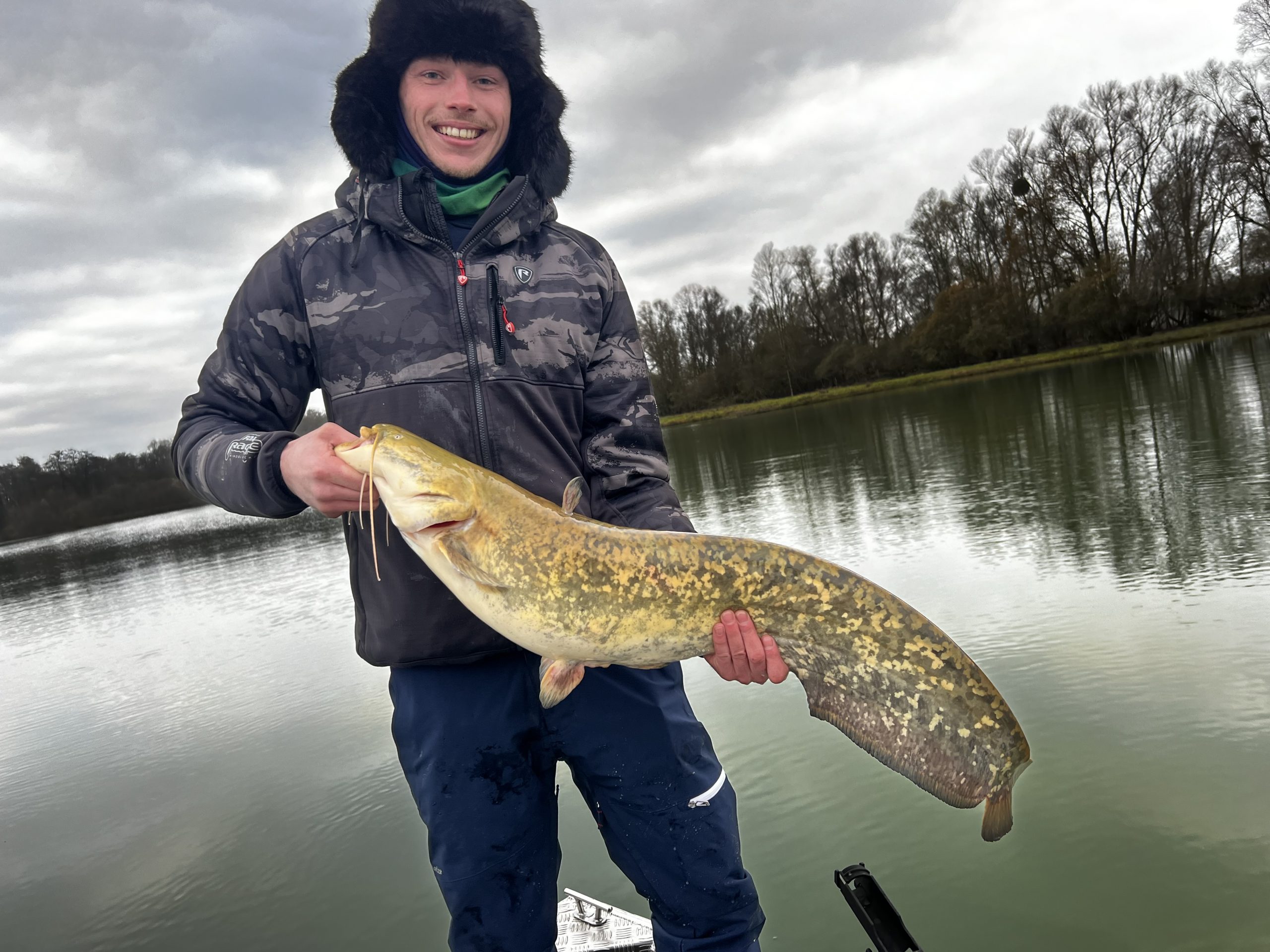 Pêche en privé sur un plan d’eau avec un pêcheur tenant un silure