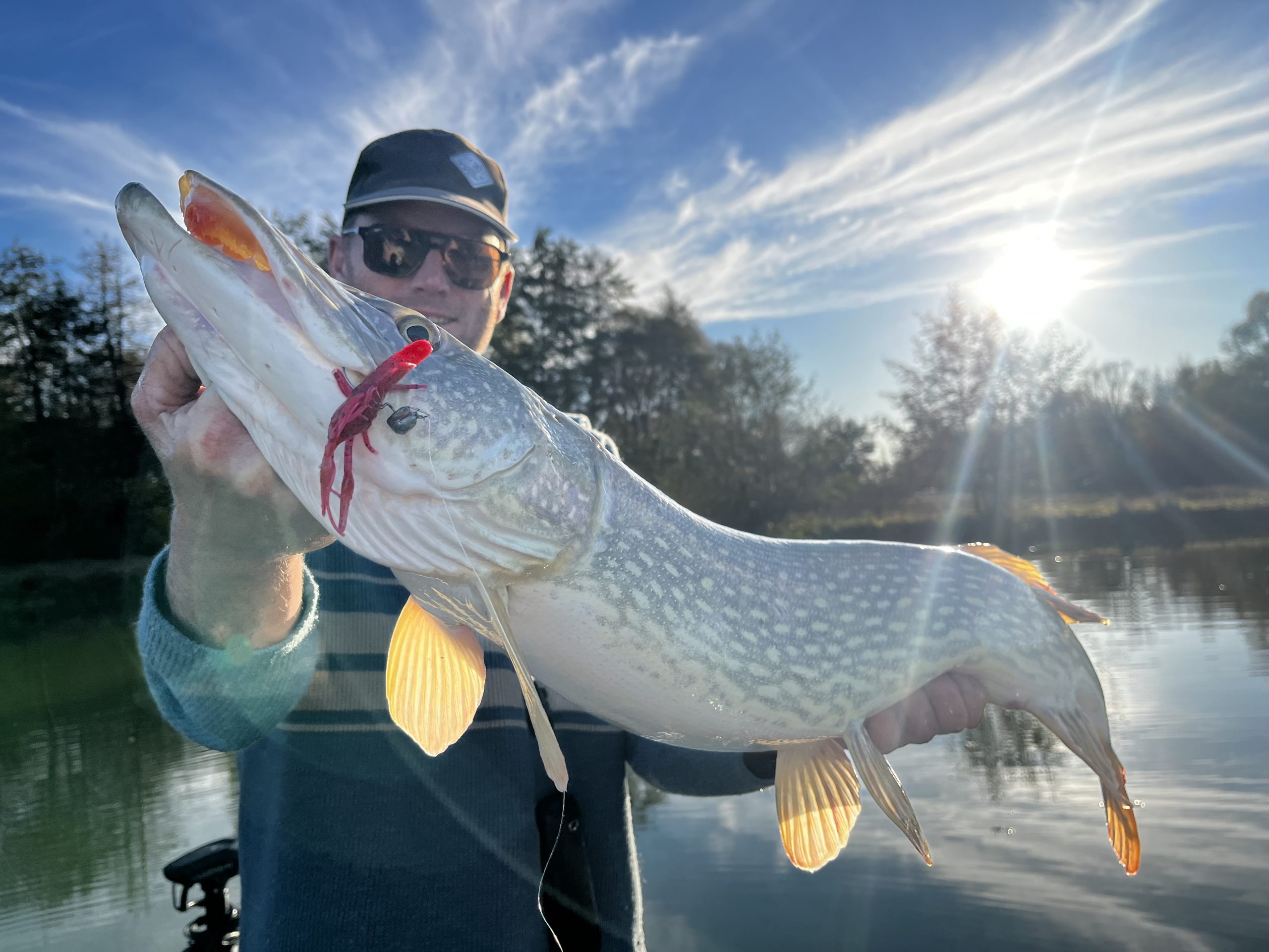 Moniteur guide de pêche tenant un brochet en automne lors d’une belle journée ensoleillée
