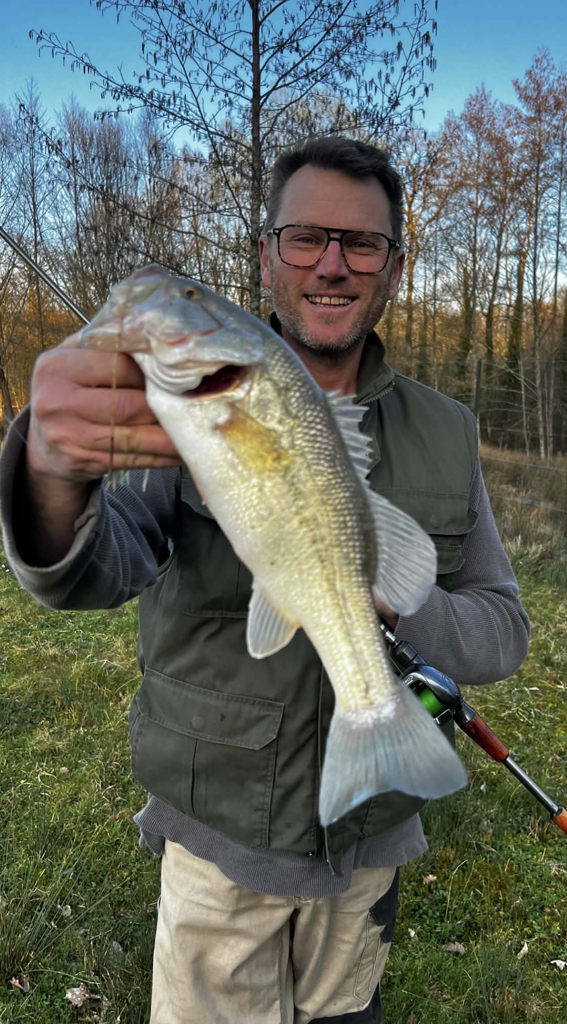 Guide de pêche tenant un black bass de 45 cm dans un étang du Grand Est